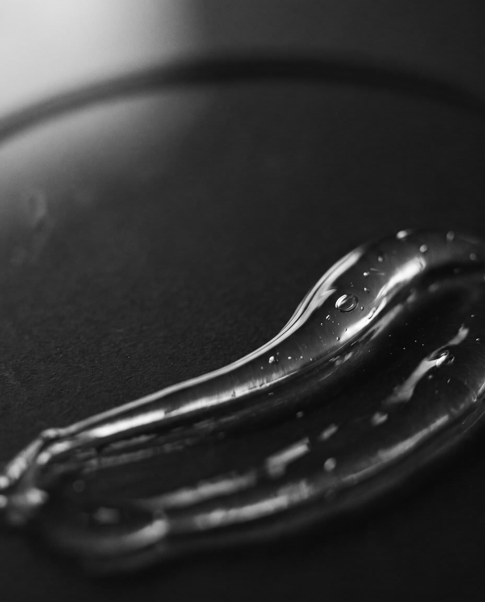 Klares Gel mit feinen Luftblasen auf dunkler, matter Fläche im Streiflicht (Beispielbild)